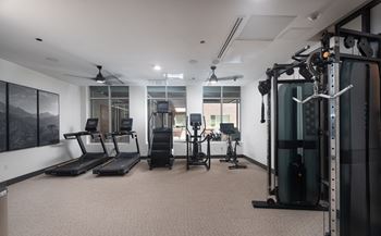 a gym with weights and mirrors in a room with a window